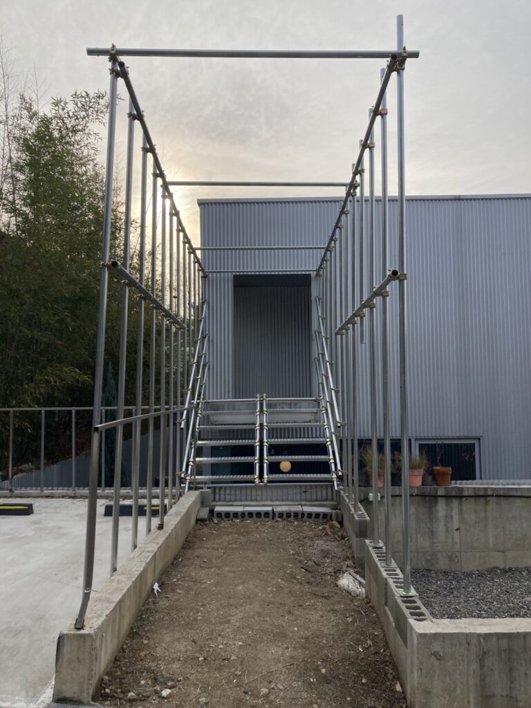 전시장 들어가는 입구. 가건물 같은 외형에 파이프로 길 입구 양쪽으로 늘어서있다.