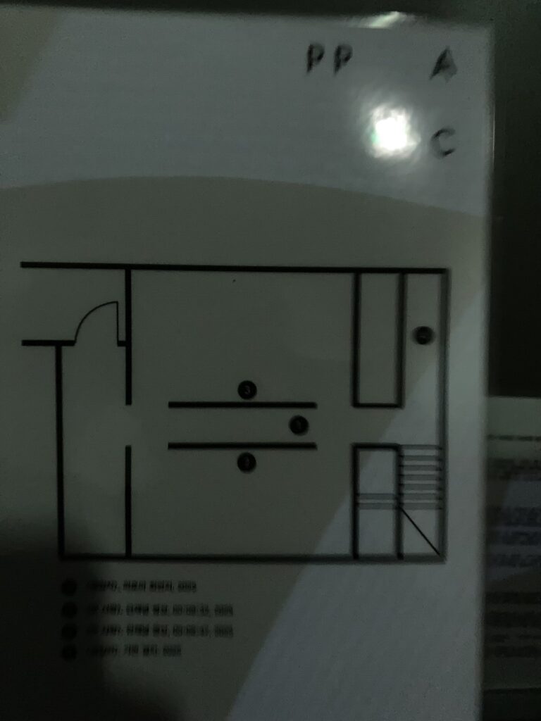 전시장 내부 배치도. 오브제와 삼면이 막힌 좁은 공간에 조명이 배치되어있고 양옆 벽면엔 두 개의 영상이 순차적으로 상영되고 있다.